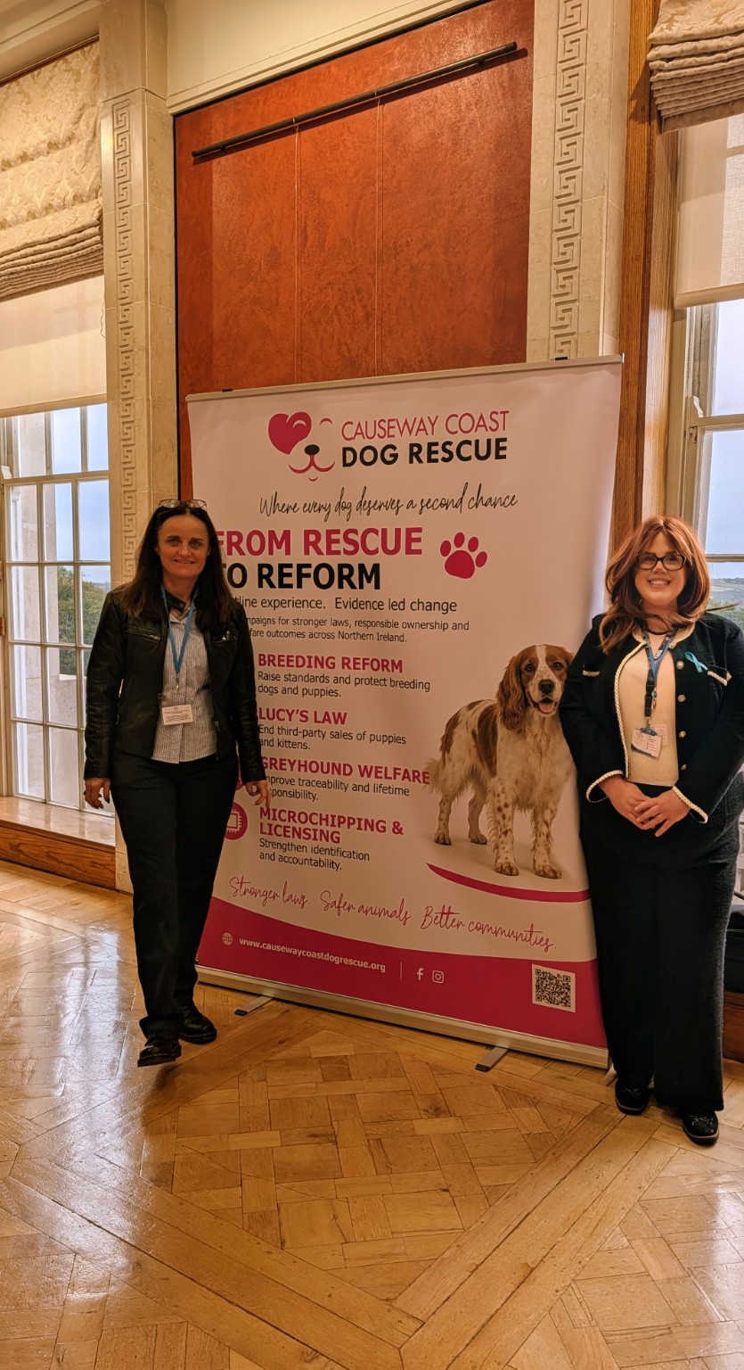 Two conference attendees beside the Causeway Coast Dog Rescue banner at Stormont