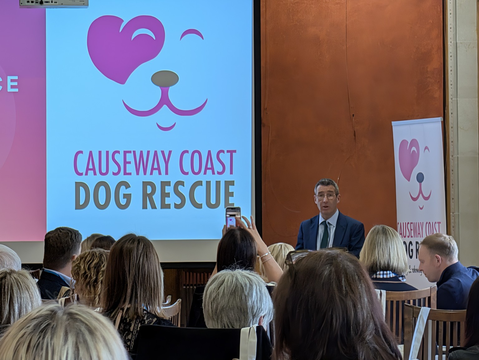 A speaker addressing the animal welfare conference beside Causeway Coast Dog Rescue branding